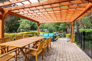 Table and chairs under a pergola with outdoor lounge area at Laurel Springs in Raleigh, NC.